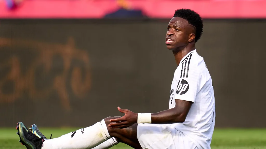 Vinicius Jr sentado no gramado do campo